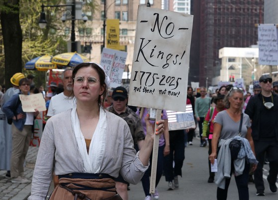 １９日にニューヨークで開かれた集会で市民が「王はいない」と書かれたプラカードを持って行進している。［写真 ロイター＝聯合ニュース］