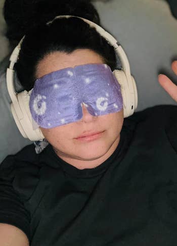 Person wearing headphones and an eye mask with a relaxing pattern, possibly promoting sleep or relaxation products