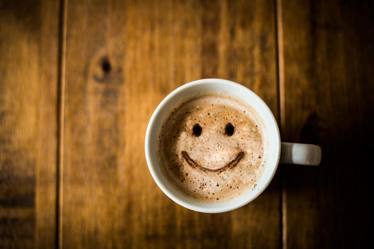 A sad looking Coffee Cup on a brown rustic table.