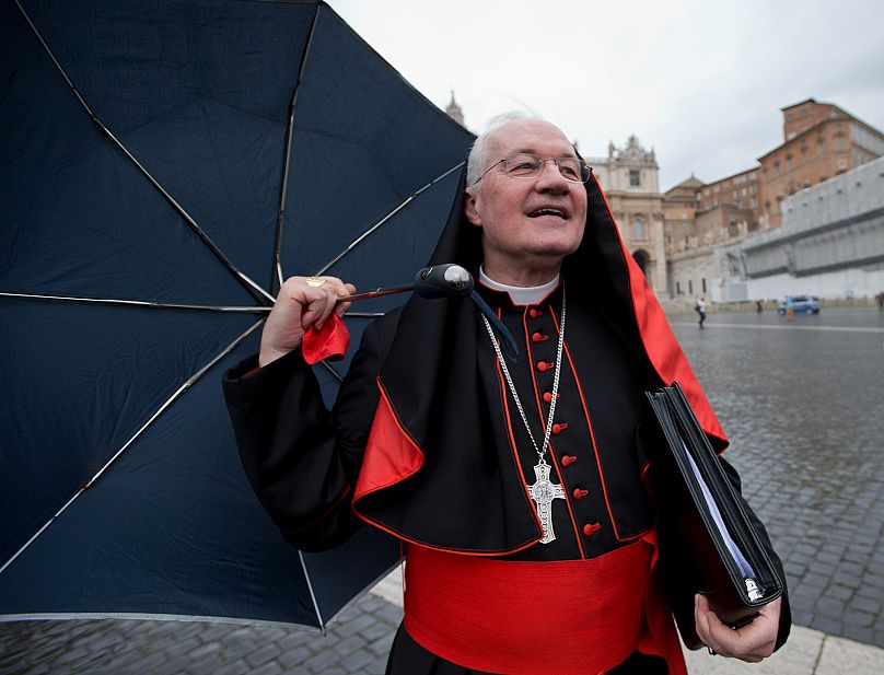 Canadian Cardinal Marc Ouellet holds on to his umbrella and his skull cap on a windy day as he walks in St. Peter's Square at the Vatican, 6 March, 2013 AP Photo