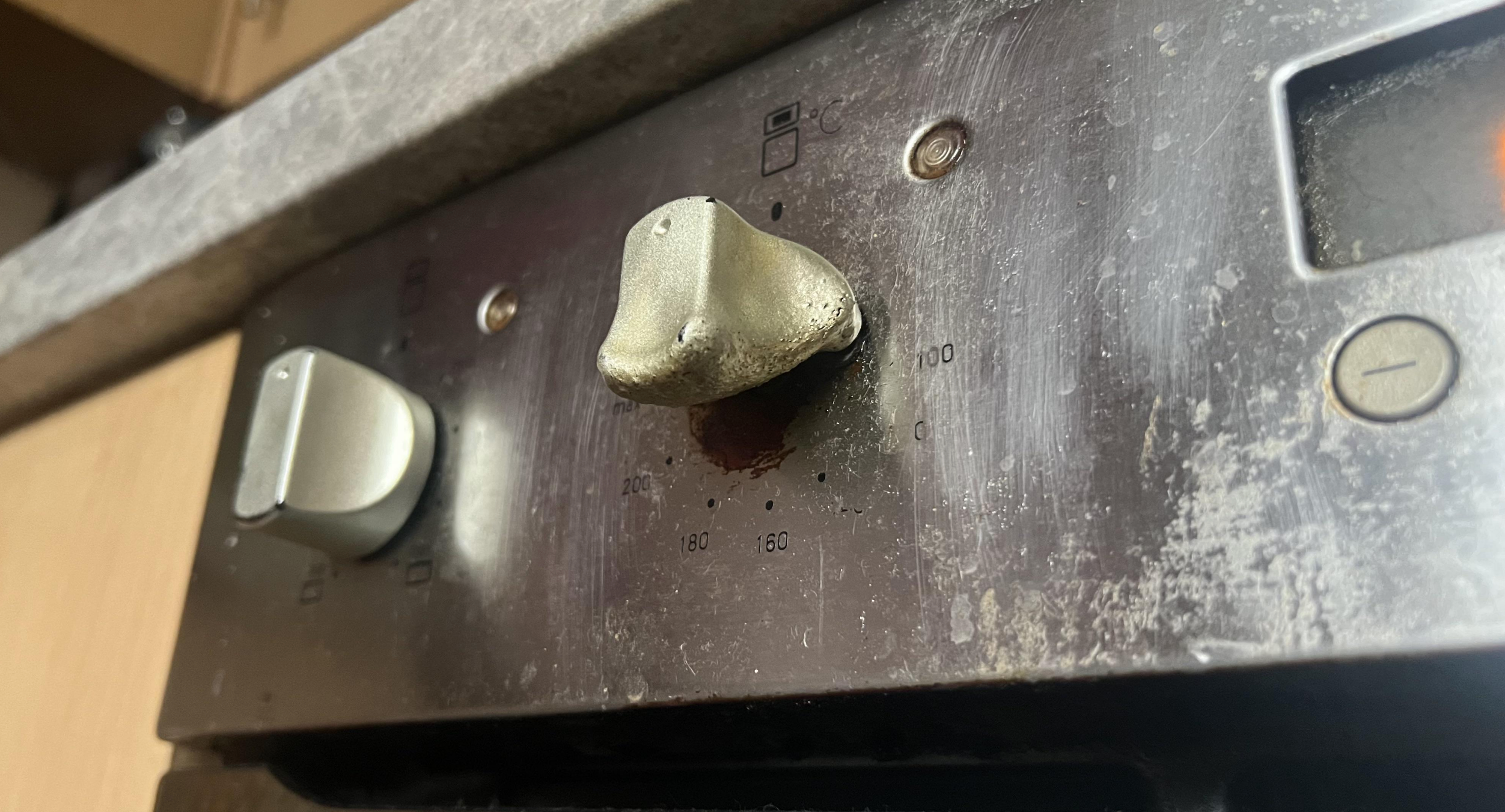 Close-up of an oven control panel with visible wear, showing three knobs