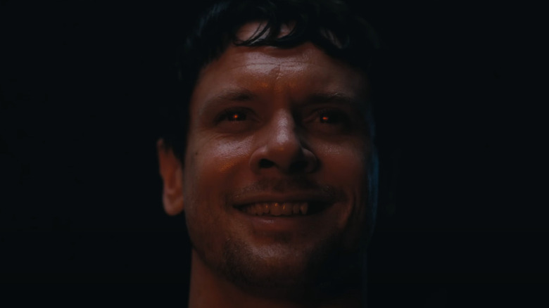 Jack O'Connell as Remmick showing his teeth with glowing red eyes in Sinners