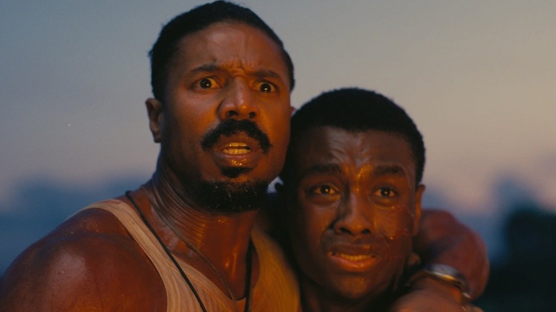 Michael B. Jordan as Stack and Miles Caton as Sammie looking in horror in Sinners