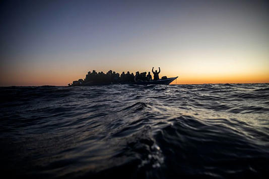 Migrants and refugees wait for assistance on an overcrowded wooden boat in the Mediterranean Sea off the Libyan coast, 12 February, 2021 AP Photo