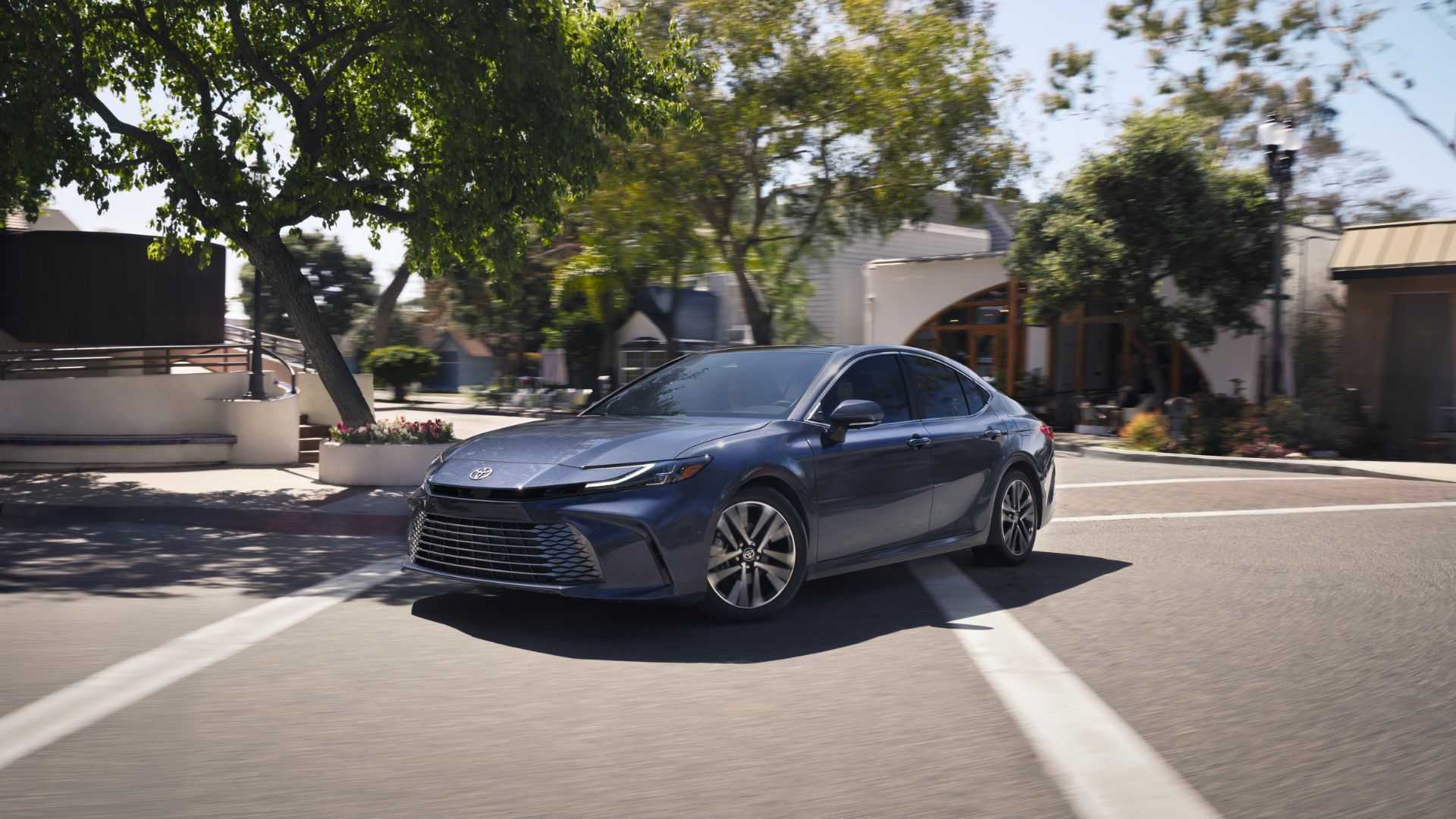 Dynamic front 3/4 shot of a gray 2026 Toyota Camry driving through a city.