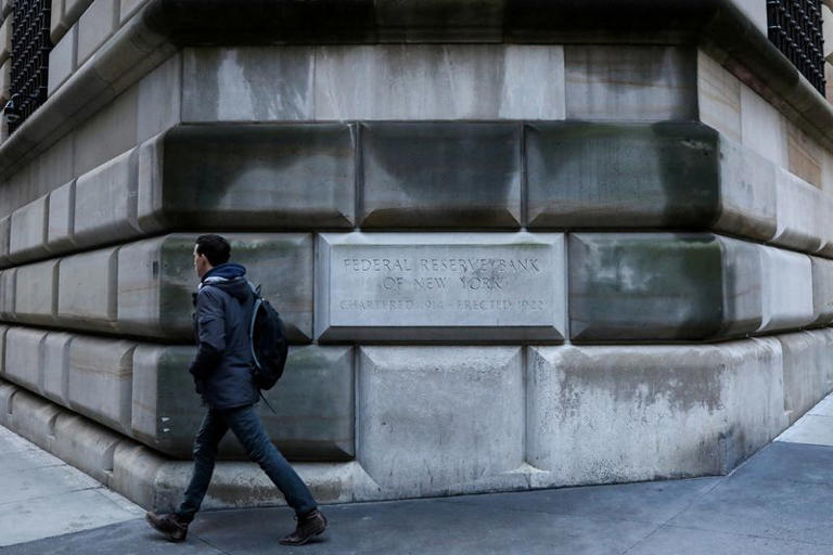 FILE PHOTO: A man passes by the corner stone on the Federal Reserve Bank of New York in the financial district in New York City, U.S., March 4, 2019. REUTERS/Brendan McDermid/File Photo