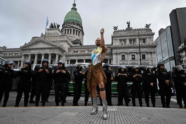 Artista performa em frente a policiais que protegem o Congresso argentino durante um protesto contra Milei em 7 de maio Foto: Luis Robayo/AFP