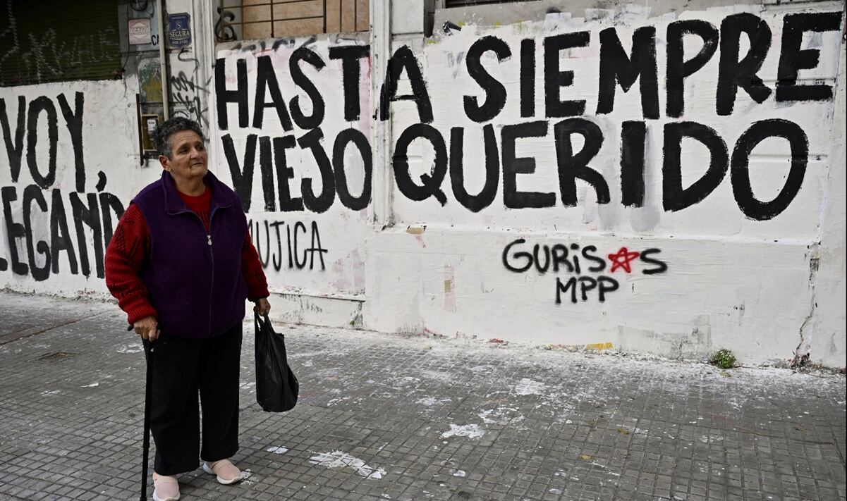 Una mujer pasa frente a un grafiti que dice: "Adiós querido viejo" durante el paso del cortejo fúnebre del expresidente José Mujica en Montevideo, Uruguay, el miércoles 14 de mayo de 2025. Foto: AP