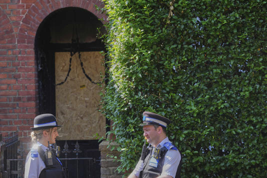 Police Community Support Officers stand near the fire damaged doorway of the house where Keir Starmer lived in Kentish Town before moving to Downing Street (AP)