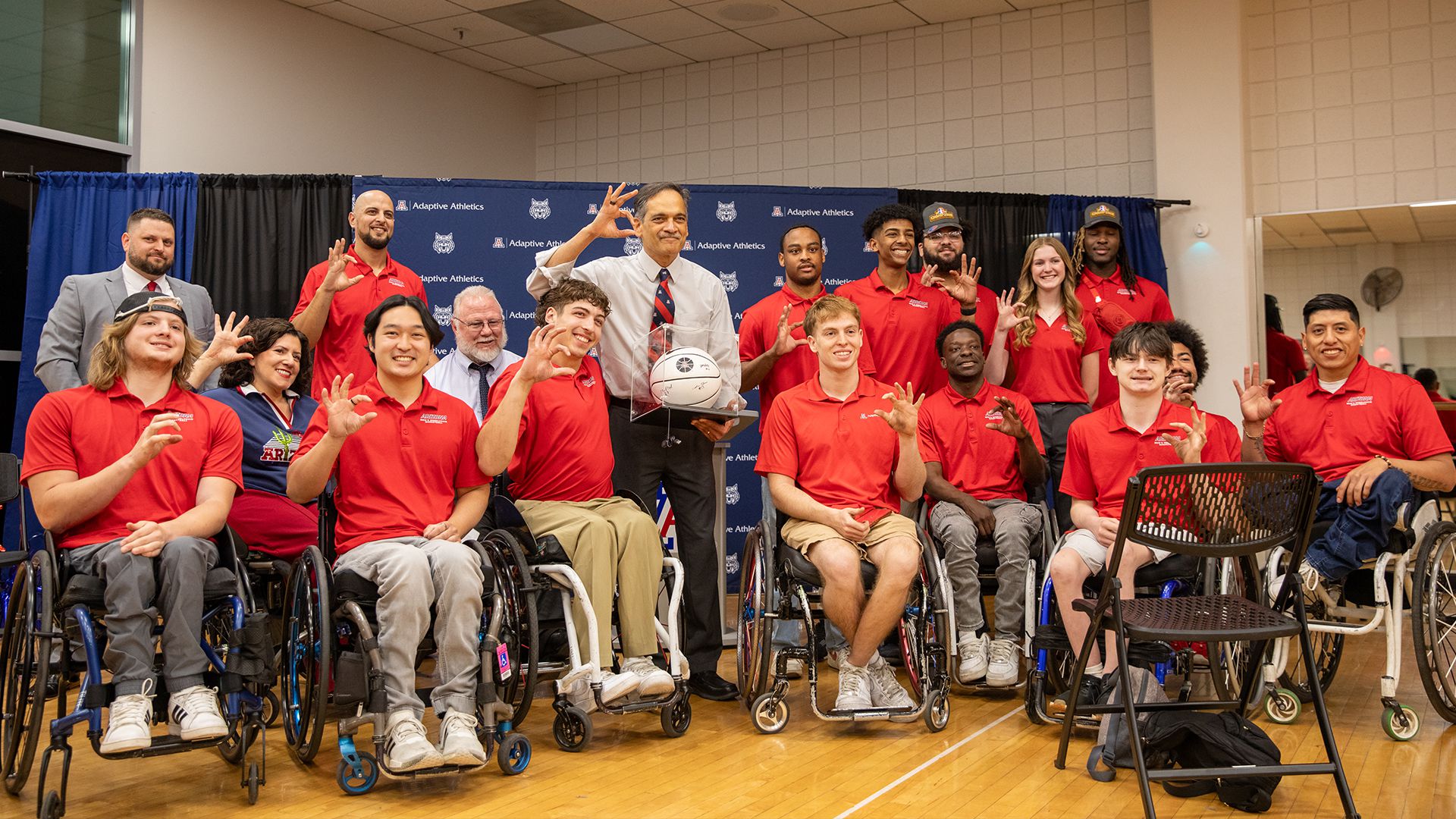 Adaptive Sports - group of wheelchair basketball players huddling up and laughing together, emphasizing the community and friendship aspect.