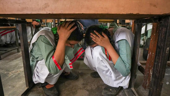 School students crouch under a desk during a drill conducted as part of a nationwide civil defence exercise, in Ghaziabad on Wednesday.