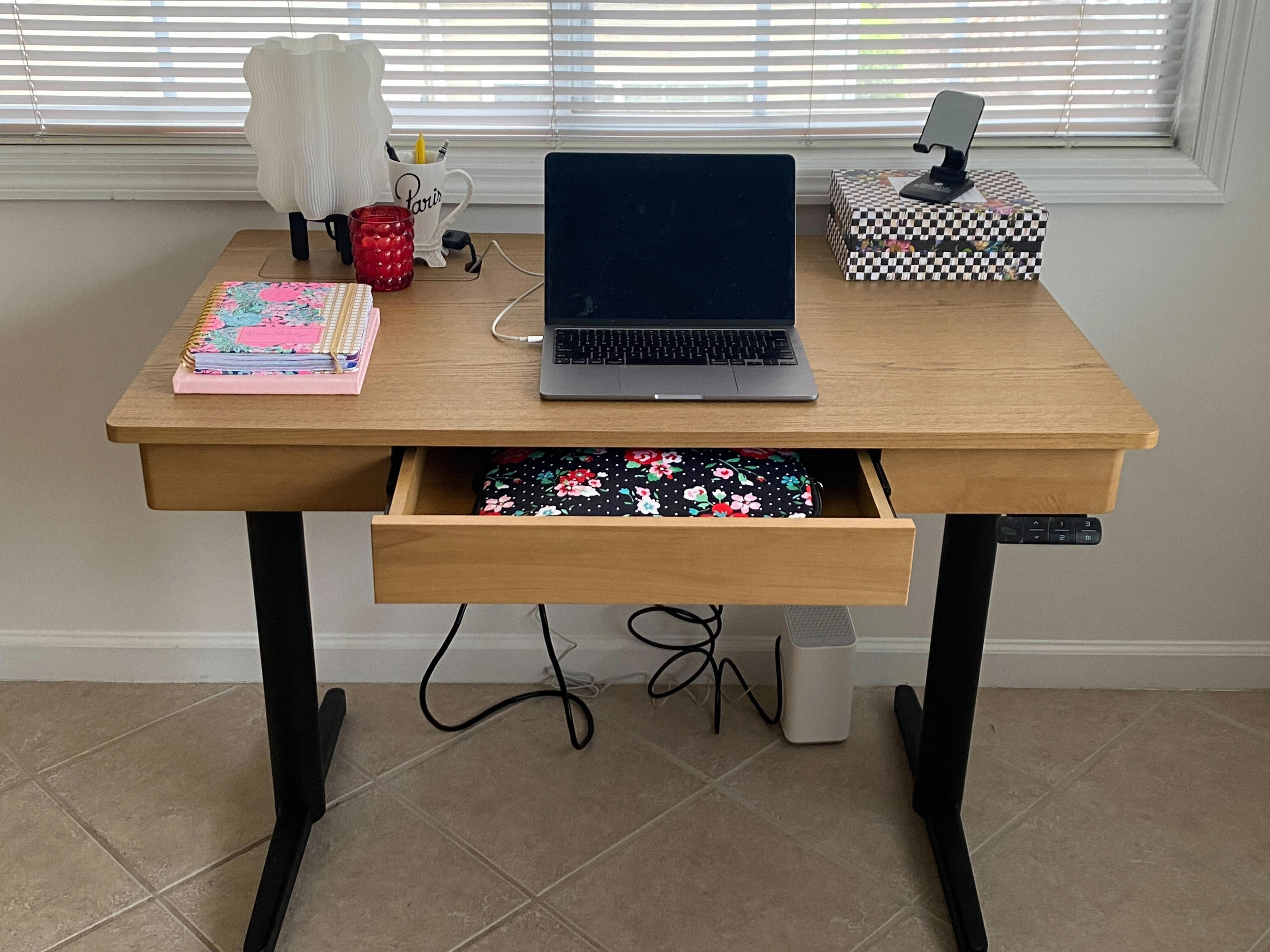 burrow standing desk with a laptop and other accessories on top. drawer is open to reveal a laptop case that demonstrates size of drawer