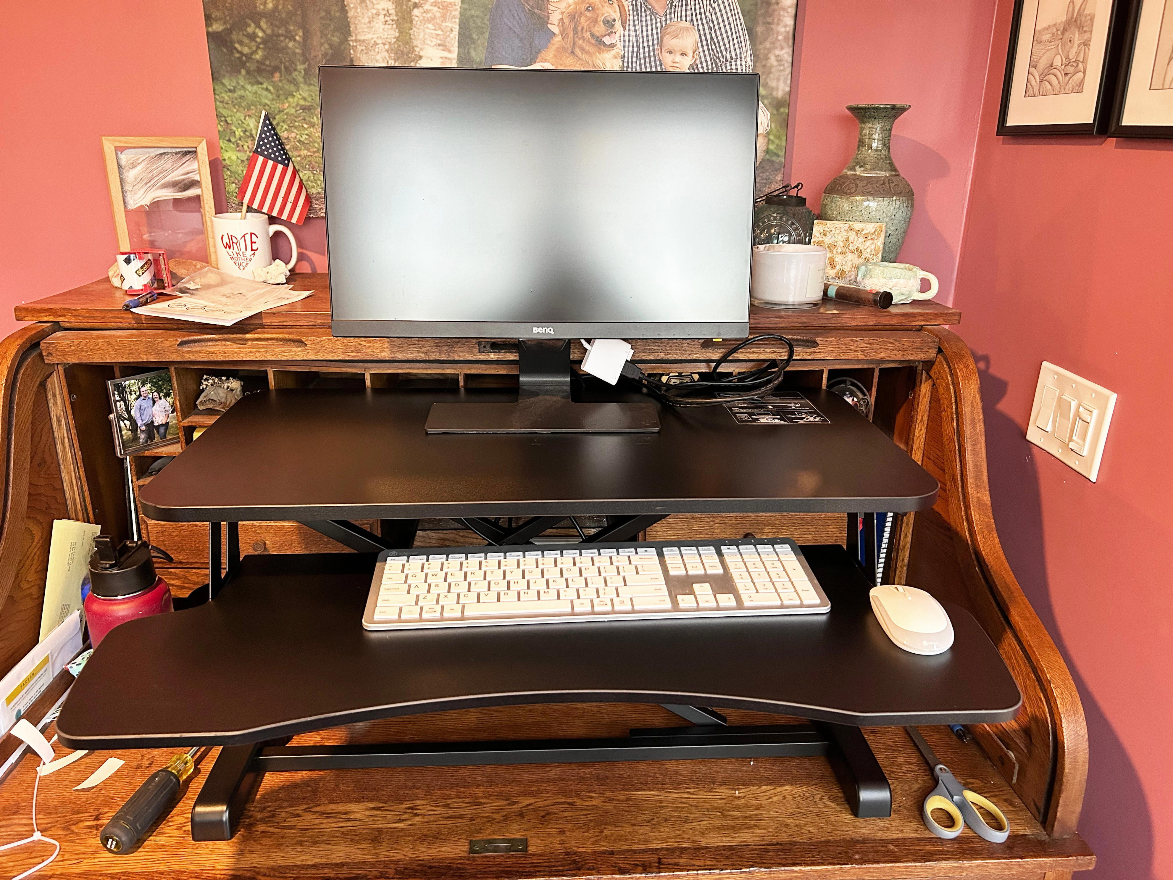 A standing desk converter, laptop, and monitor on a wooden desk.