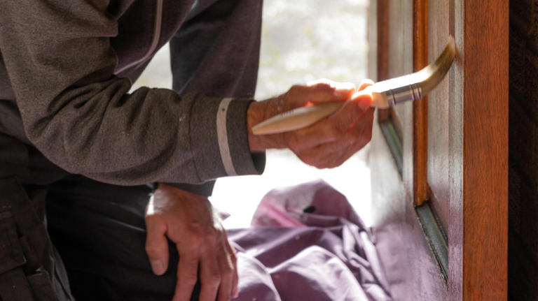 A man paints a wooden door with a paint brush