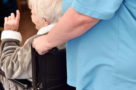 Care home staff help elderly people move about the care home, Yorkshire UK