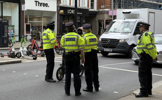 Police stopping an e-bike rider in High Street Kensington to check his cycle is road worthy (ES)