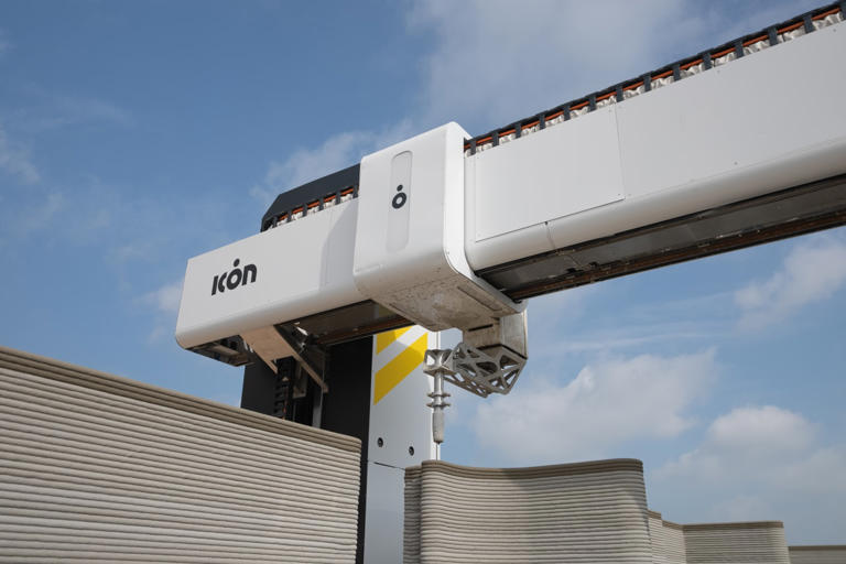 An ICON system uses 3-D printing to add concrete to the framing of a home.