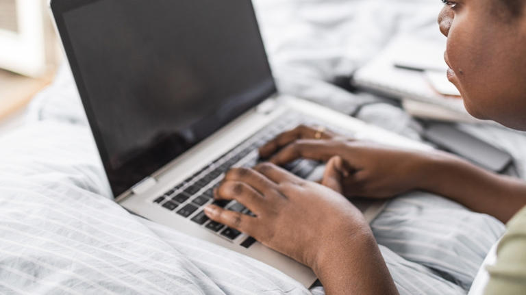 Woman using laptop on bed