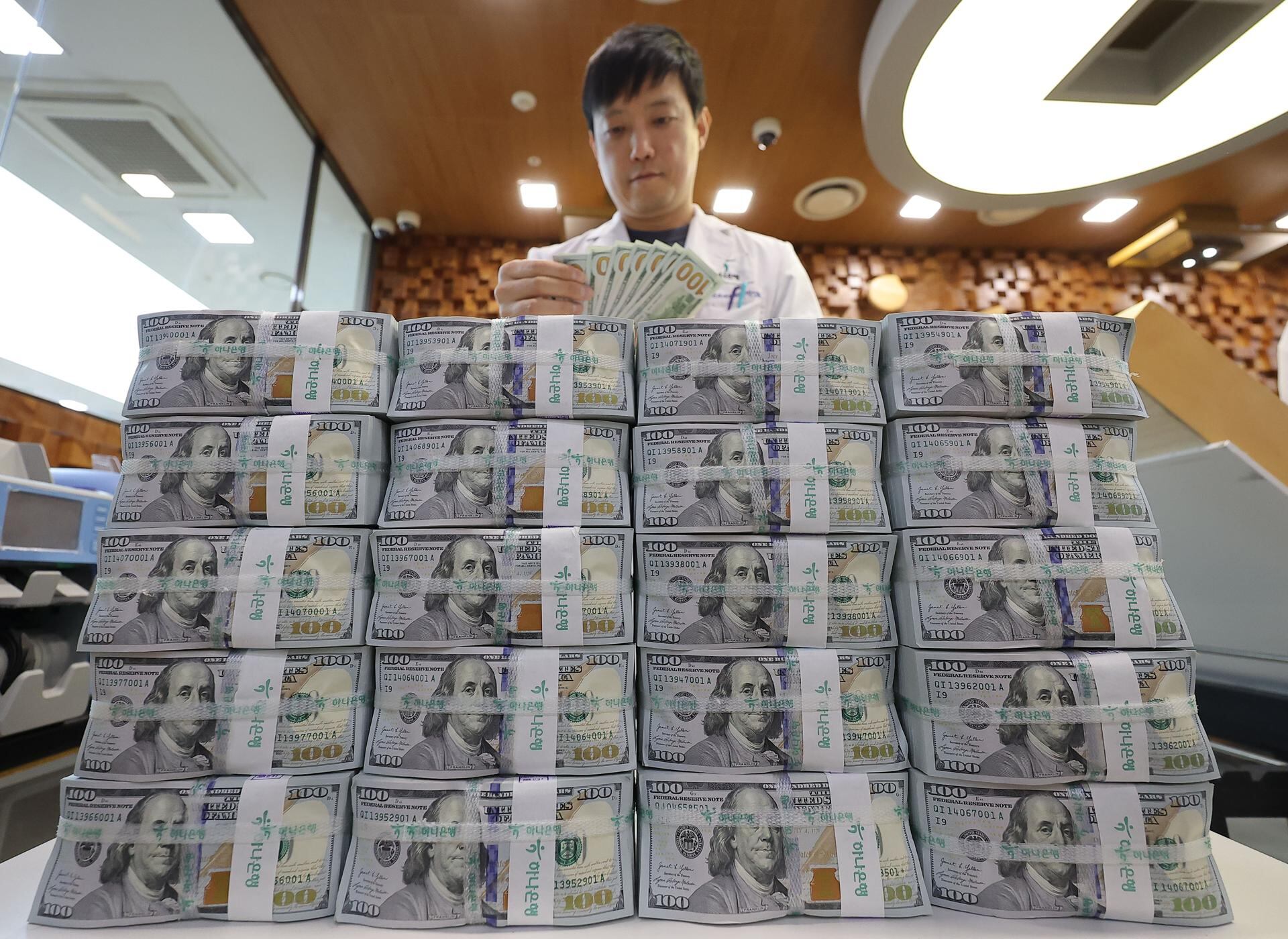 Un empleado clasifica billetes de 100 dólares estadounidenses en la sede del Banco Hana en Seúl, Corea del Sur. Imagen de referencia.