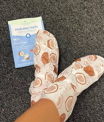 Person wearing hydrating socks with coconut design, next to a package indicating the product's moisturizing benefits with natural coconut oil
