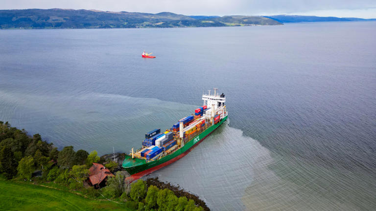 An areal view shows a 135-meter-long container ship by the shore in the Trondheimsfjord outside Byneset by Trondheim Norway on May 22 2025 after it ran aground almost hitting a house  Credit JAN LANGHAUGNTBAFP via Getty Images