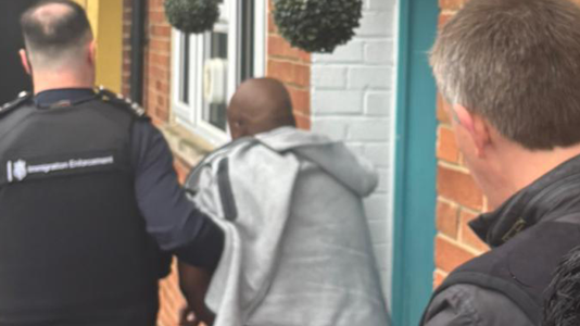 A man is led away by immigration enforcement officers. Pic: Home Office
