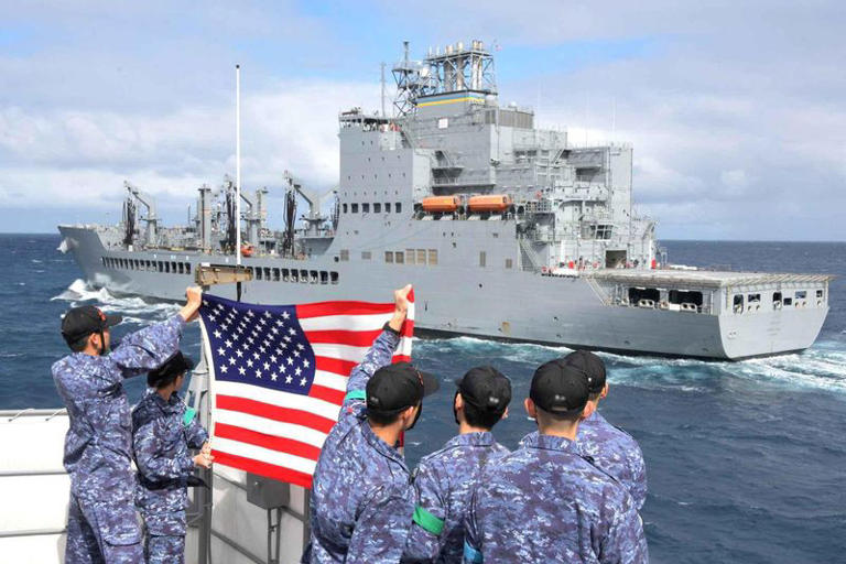 FILE PHOTO: Crewmembers of Japanese Maritime Self Defense Force guided missile destroyer JS Shimakaze hold a U.S. flag towards the U.S. Navy oiler USNS Harvey Milk during an exercise in the Virginia Capes’ (VACAPES) operating area in the Atlantic Ocean, September 24, 2024. LaShawn Sykes/U.S. Navy/Handout via REUTERS/File Photo