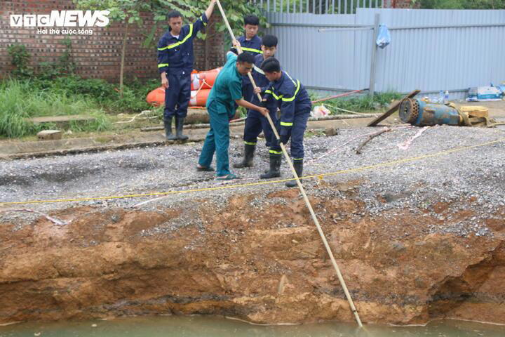 Lực lượng chức năng dùng câu liêm, sào gắn móc để chọc xuống đáy hố tìm kiếm nạn nhân.
