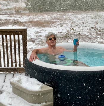 reviewer relaxing in the hot tub while it snows