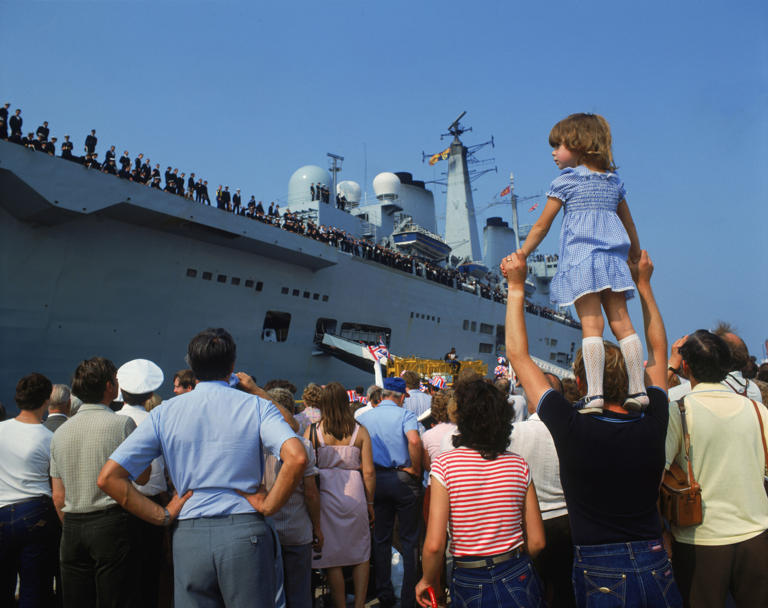 HMS Invincible, a light aircraft carrier, played a key role in the Falklands War as part of the Royal Navy's carrier strike group. Embarked with Sea Harriers from 800 and 801 Naval Air Squadrons, she provided continuous air defence, strike missions, and reconnaissance. Operating alongside HMS Hermes, Invincible helped maintain air superiority over the islands. Her Sea Harriers downed several Argentine aircraft. Though under threat from submarines and missiles, she remained undamaged and vital to British control of the air throughout the conflict. Pictured: HMS Invincible returns to Portsmouth, carrying British troops home from the Falklands War,