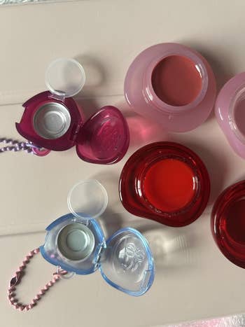 Heart-shaped lip balms and red lip gloss pots displayed on a table for a shopping article