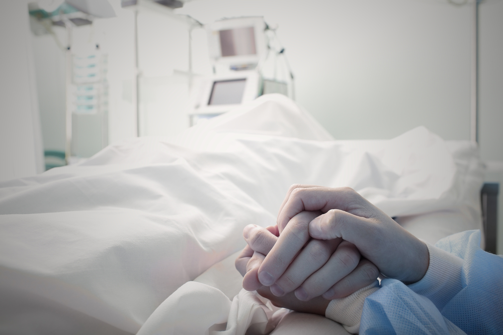 две женщины в больничной палате, одна держит за руку другую