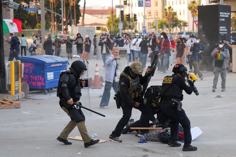 Police detains a protester blocking the garage entrance of the Los Angeles Federal Building following multiple detentions by Immigration and Customs Enforcement (ICE).