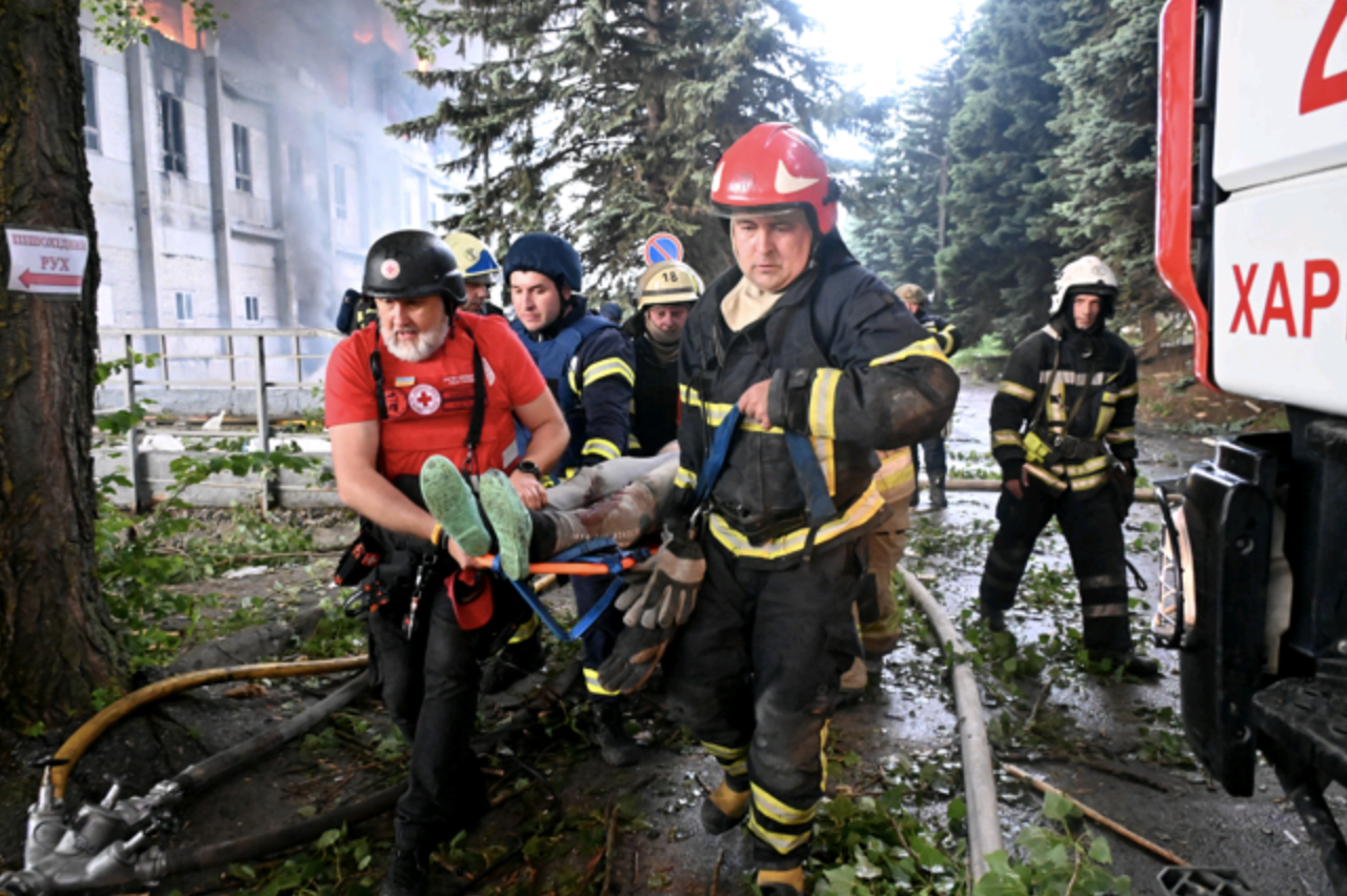 Rescuers carry a wounded person following the Kharkiv attack (AFP)