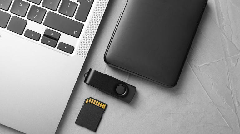 Laptop with SD card, flash drive and hard drive next to it