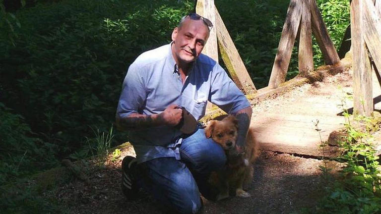 Ein privates Foto zeigt Dieter Wollny 2020 in blauem Hend neben seinem kleinen Mischlingshund knien