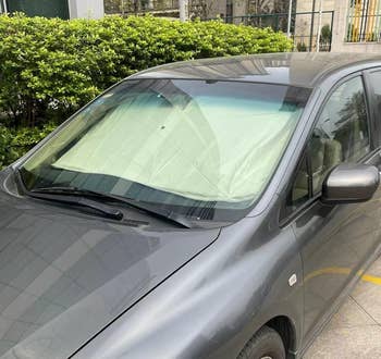 Car parked with windshield sunshade in place, protecting the interior from heat and sun damage