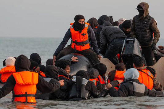 Migrants get onto a small boat in the English Channel