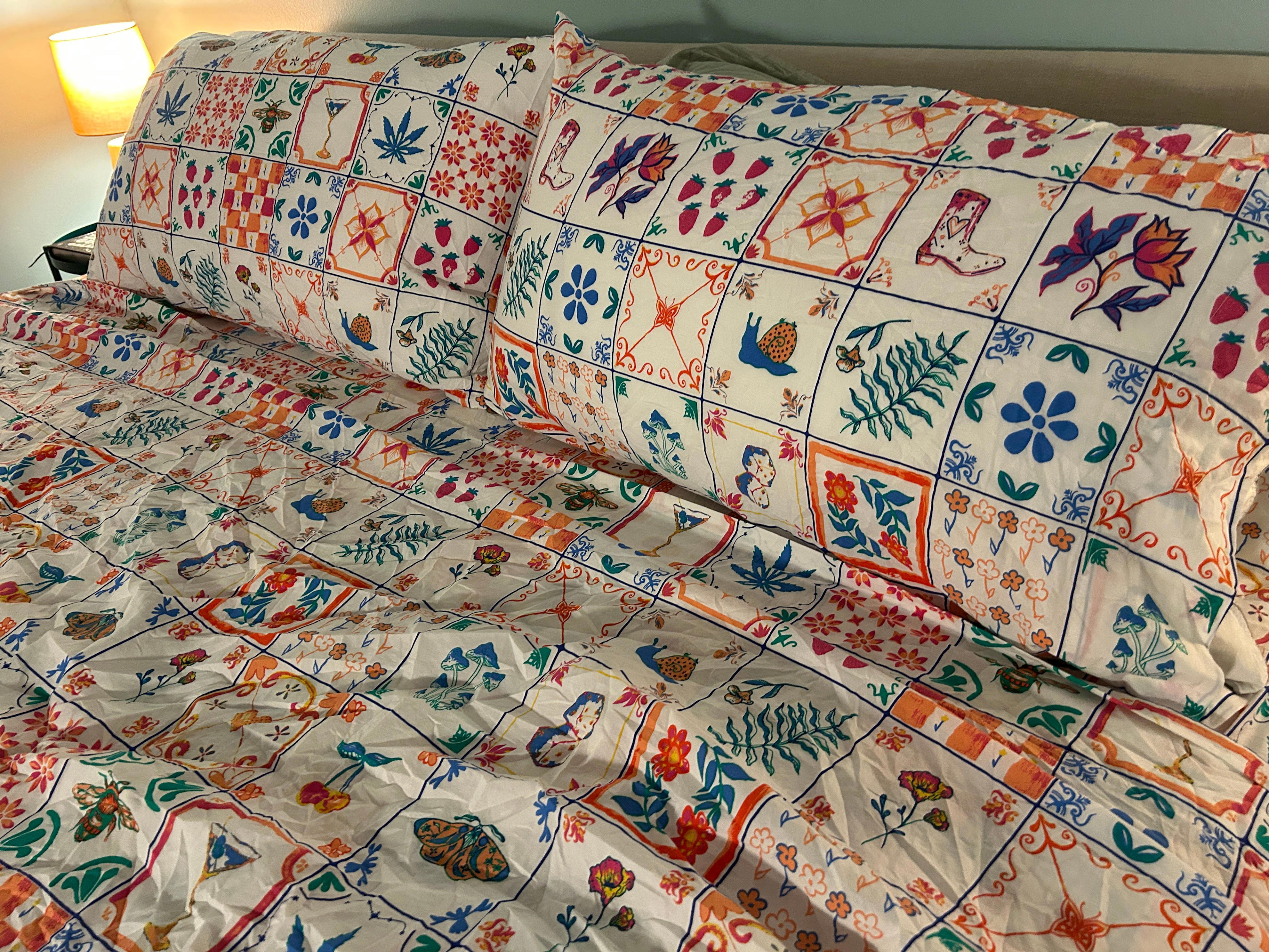 The Urban Outfitters Mariana Tile sheets on a bed. The design features tiles with floral and icon designs.