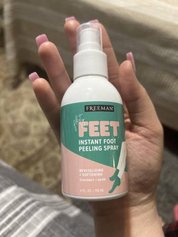 Hand holding a bottle of Freeman Flirty Feet Instant Foot Peeling Spray, featuring coconut and aloe, described as revitalizing and softening