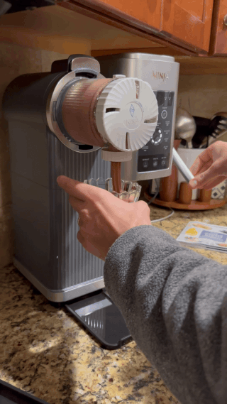 Person making soft serve ice cream with a Ninja ice cream machine on a kitchen counter, showcasing the appliance's features