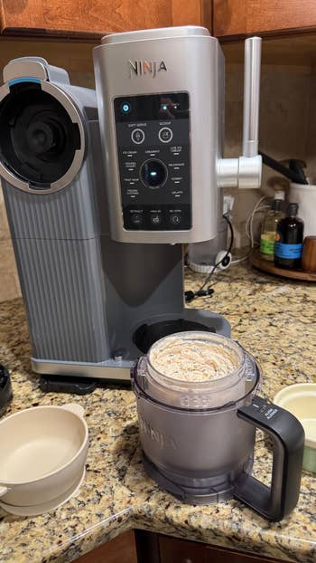 Ninja ice cream maker on a kitchen counter, with a pitcher containing freshly made ice cream, two empty bowls nearby