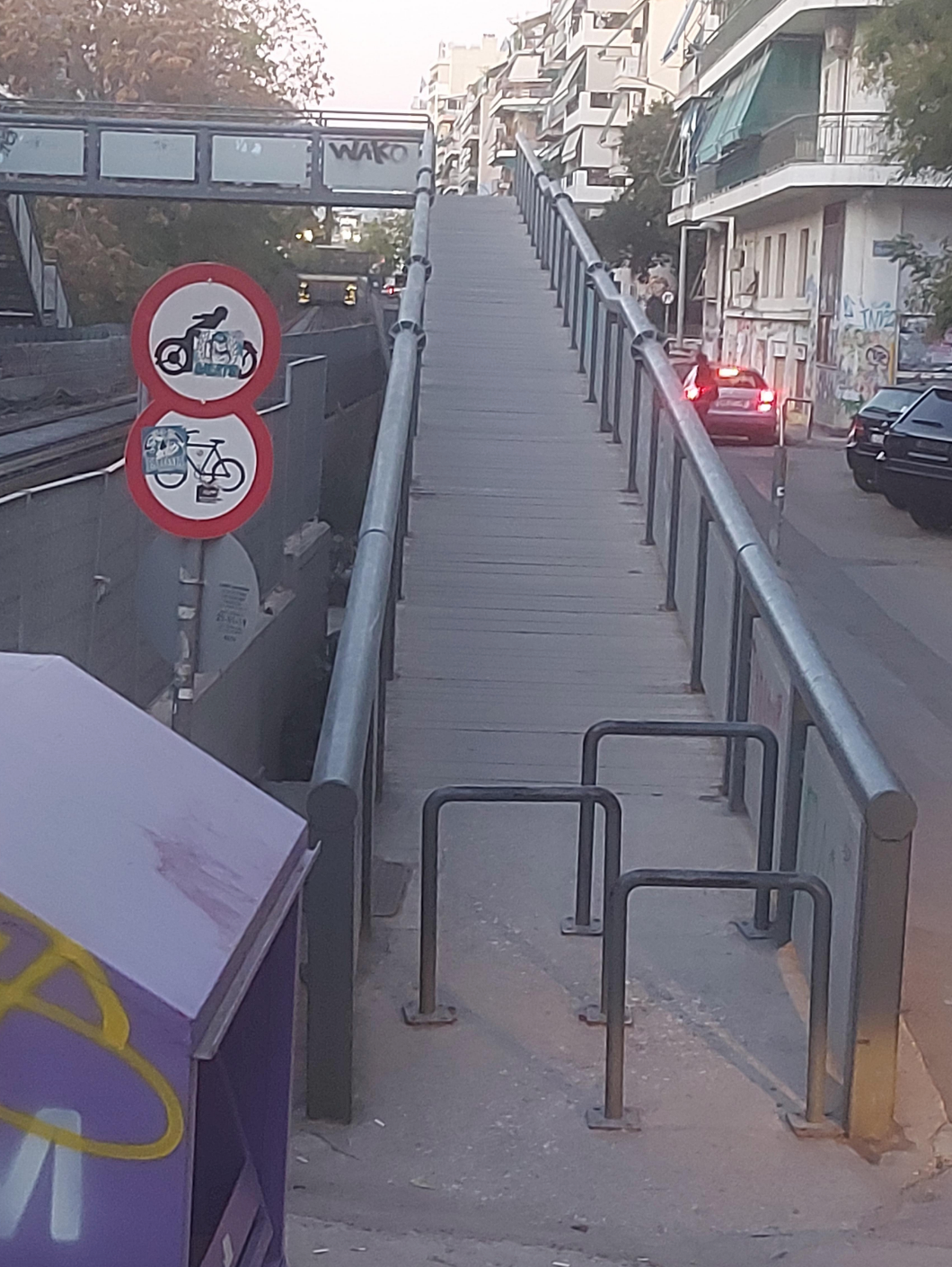 Pedestrian overpass with bike and motorcycle prohibition signs; cars visible on road nearby