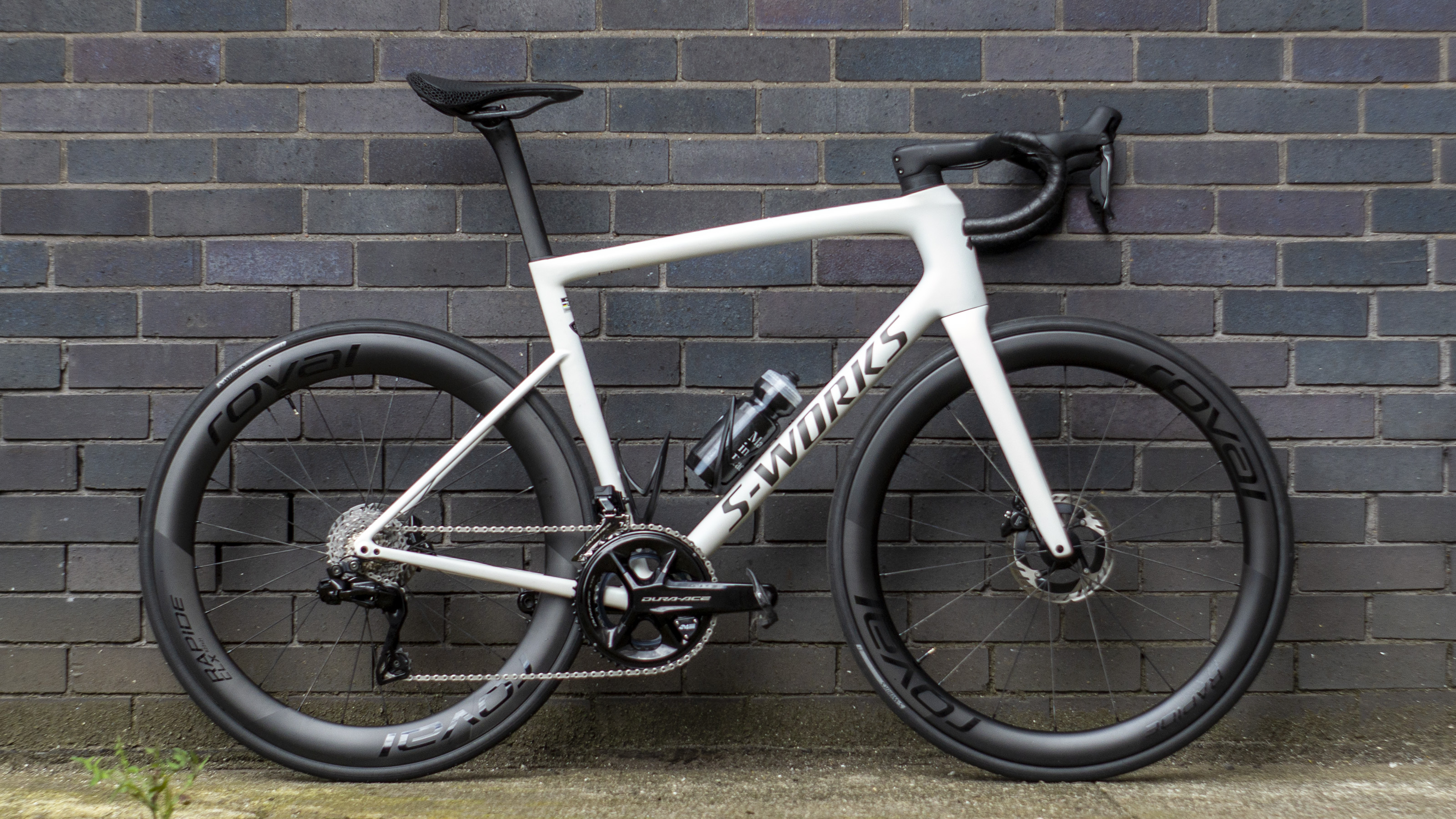 A white Specialized S-Works Tarmac SL8 stands against a wall
