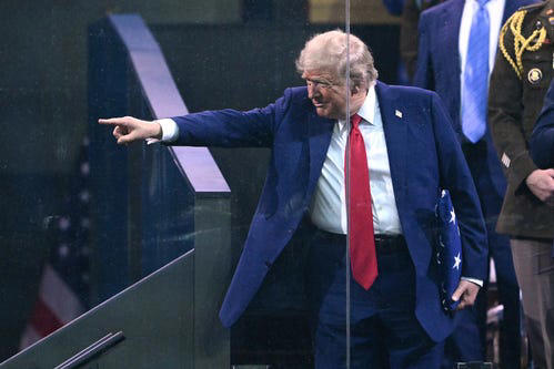 President Donald Trump points holding a US flag given to him by a member of the Army's Golden Knights after the Army 250th Anniversary Parade in Washington, DC on June 14, 2025.
