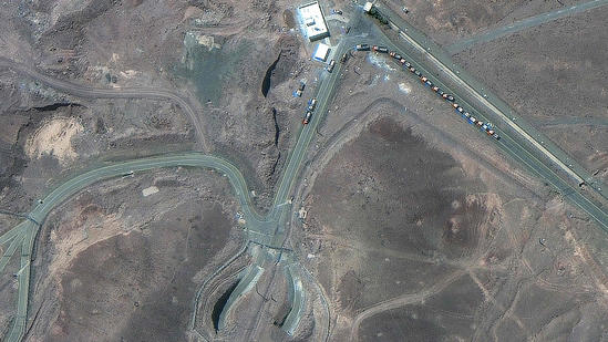 This handout satellite image courtesy of Maxar Technologies shows cargo trucks postioned near an underground entrance to Iran's Fordow Fuel Enrichment Plant.