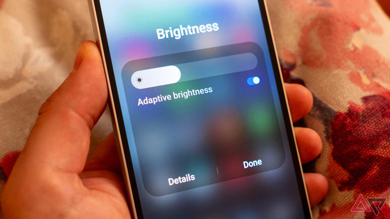 a close up of a phone in hand displaying brightness settings slider