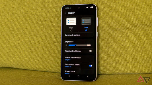 a samsung galaxy phone with dark mode enabled on a green couch