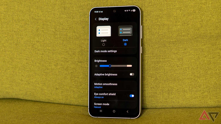a samsung galaxy phone with dark mode enabled on a green couch