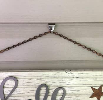 A decorative sign hands from a hook installed on a house's siding